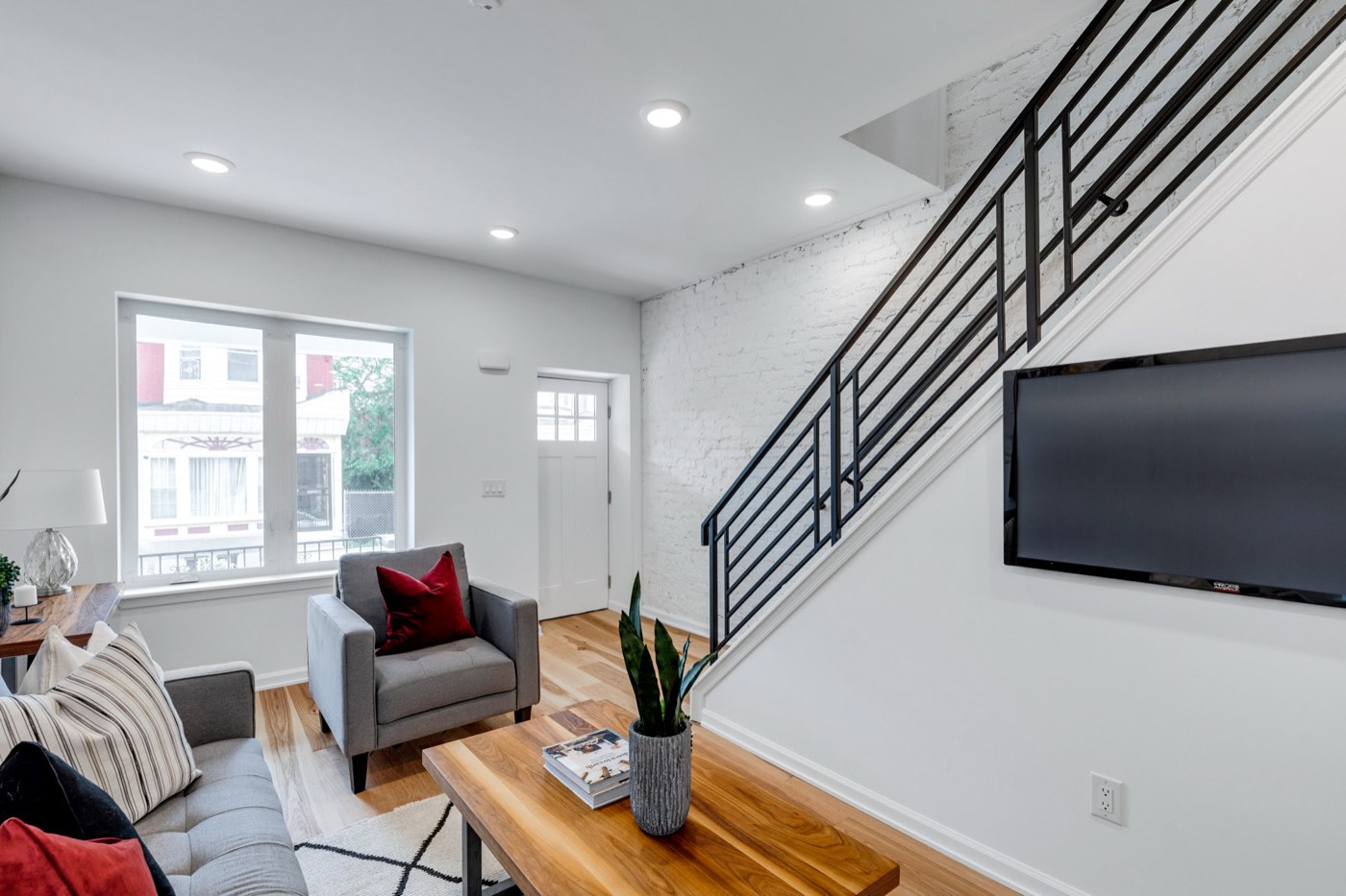 Staged living room at 710 S Frazier St with exposed painted brick and new stair rail